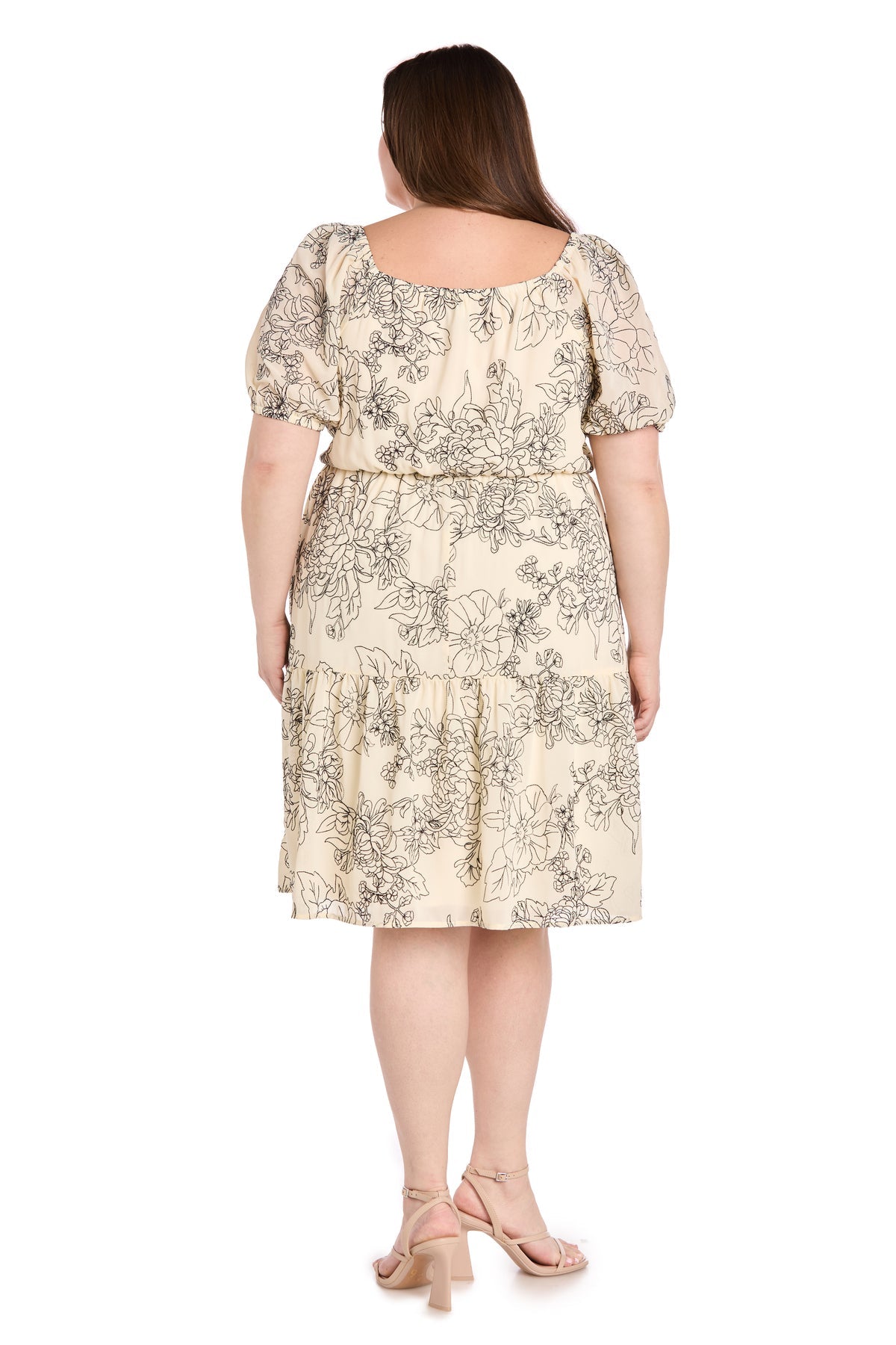 A woman is shown from the back wearing the Plus-Size Ivory Party Dress: R&M Richards 6688W, a cream-colored, knee-length floral dress with short puff sleeves, paired with sandals.